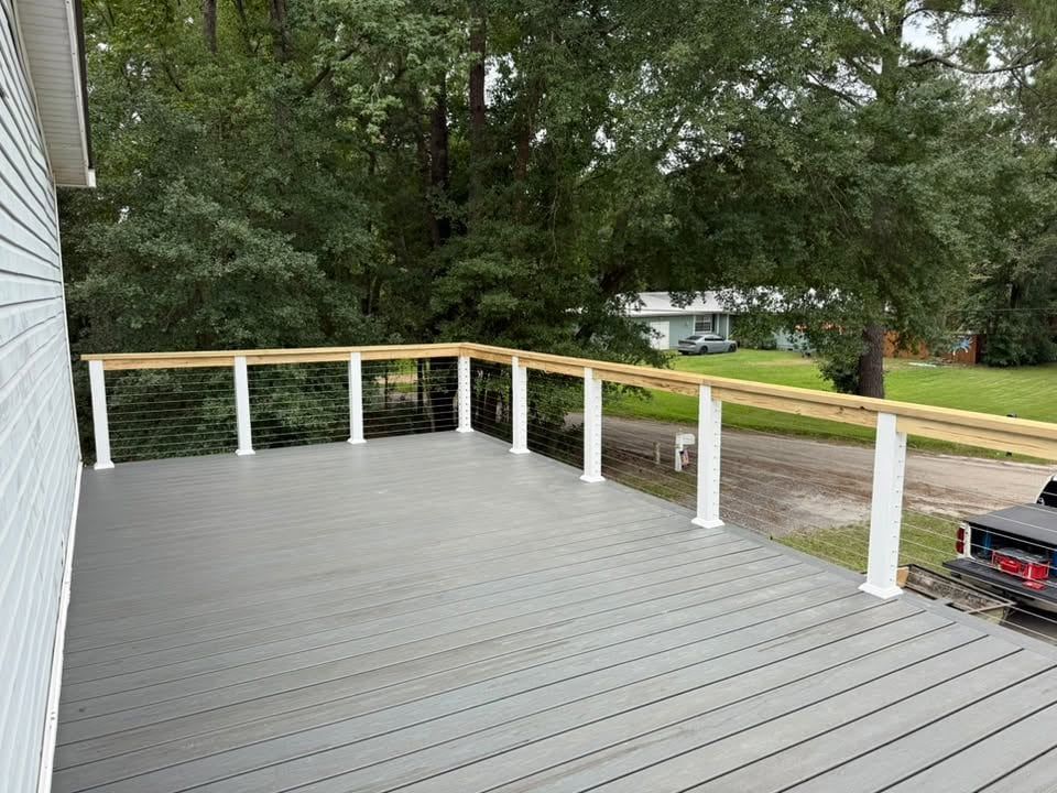 New grey composite deck with white posts, cable railing and a wood top rail
