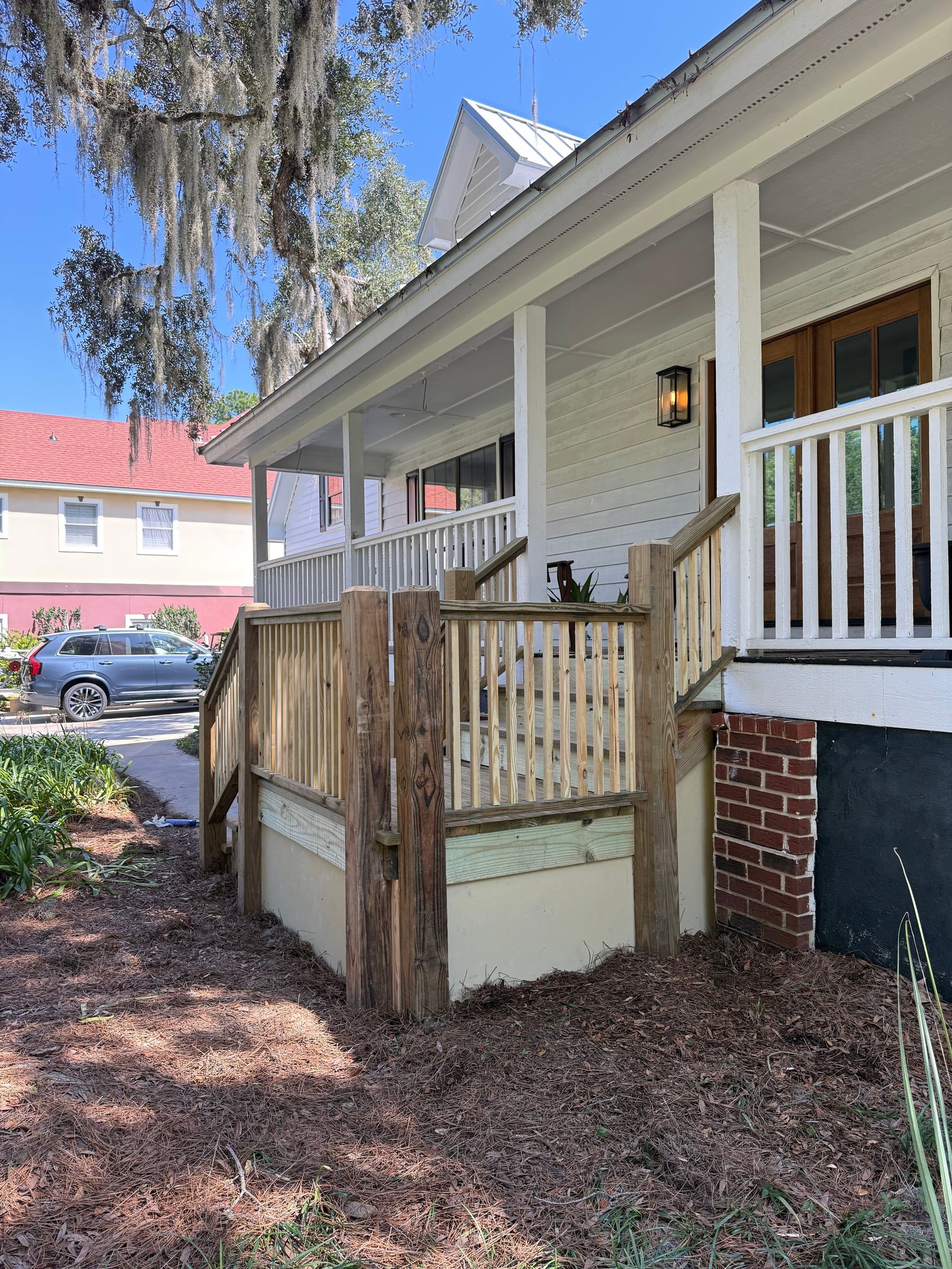 New wooden stairs and railings rising to a covered front porch