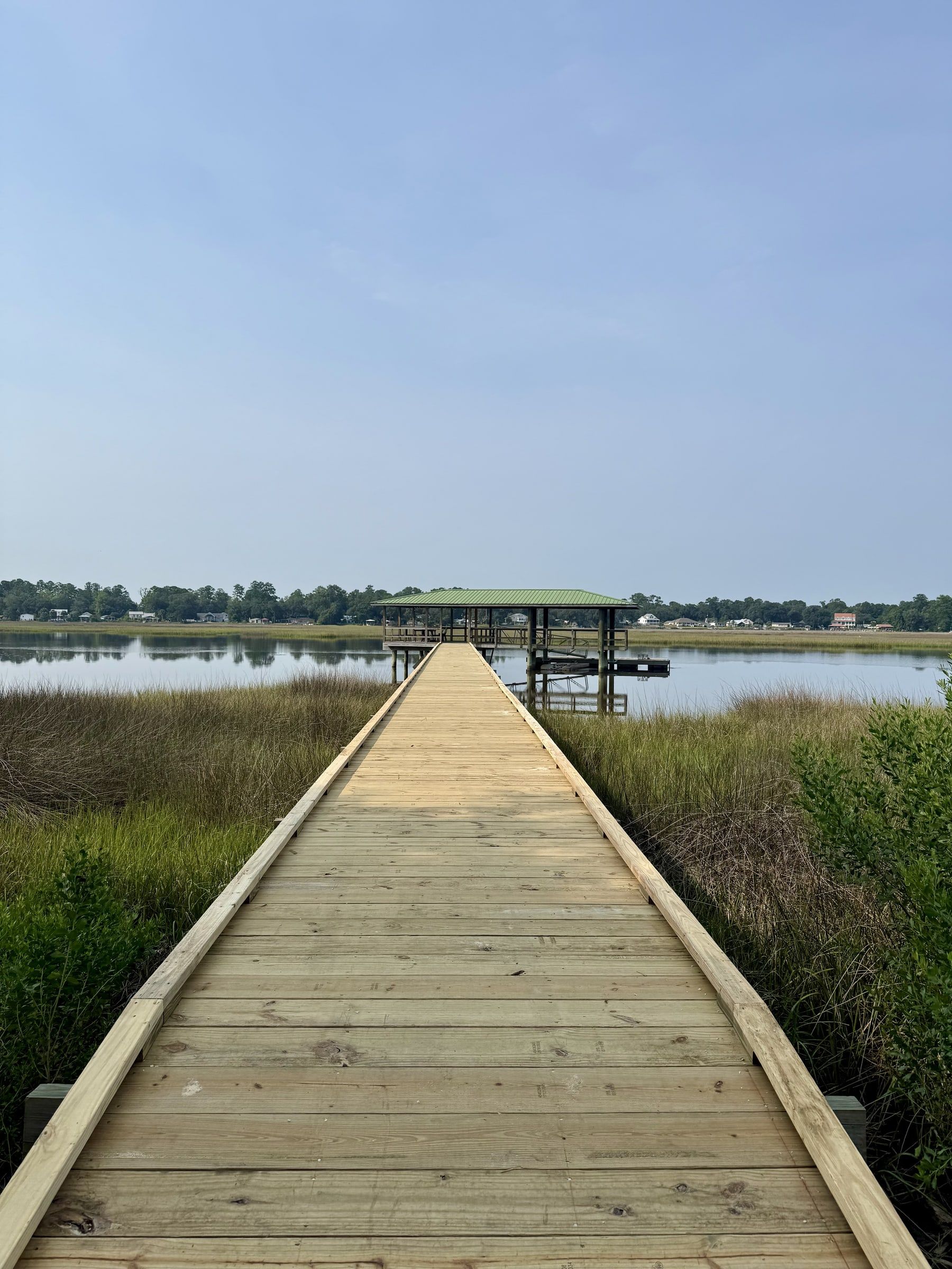 Wooden dock walkway running out across the marsh to a covered dock on the water