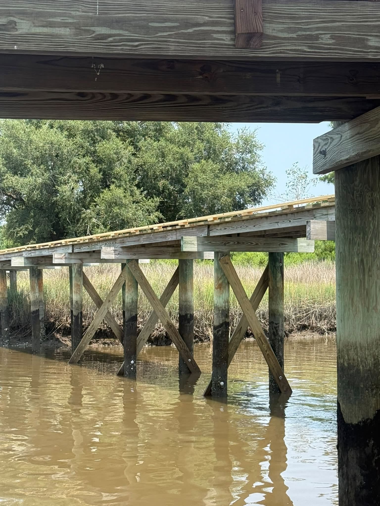 New X-bracing installed between the pilings of an existing dock over a tidal creek