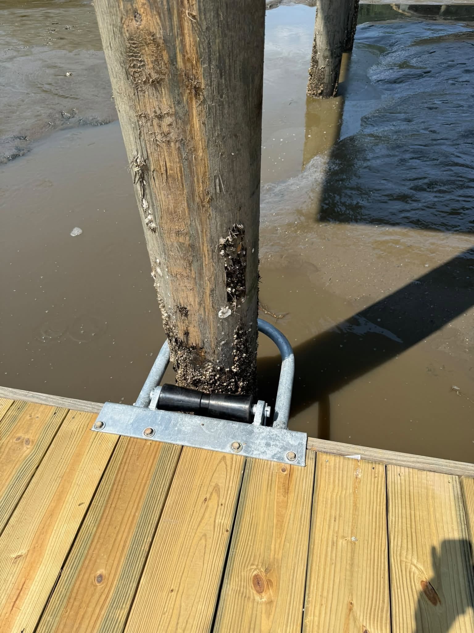 Galvanized pile hoop and roller holding a floating dock to its piling