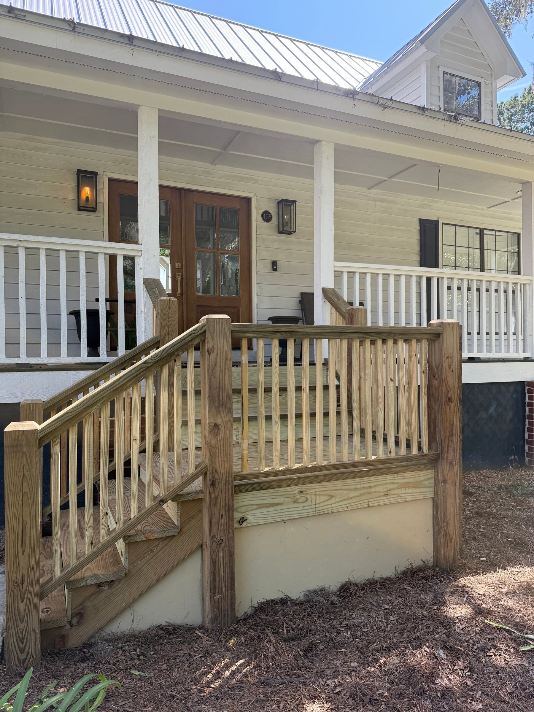 New pressure-treated wood porch steps and railings at the front door of a white house