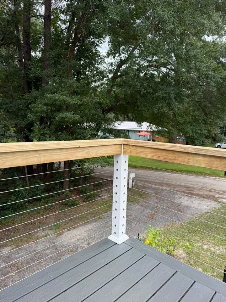 Close-up of stainless cable railing with a wood cap rail on a raised deck