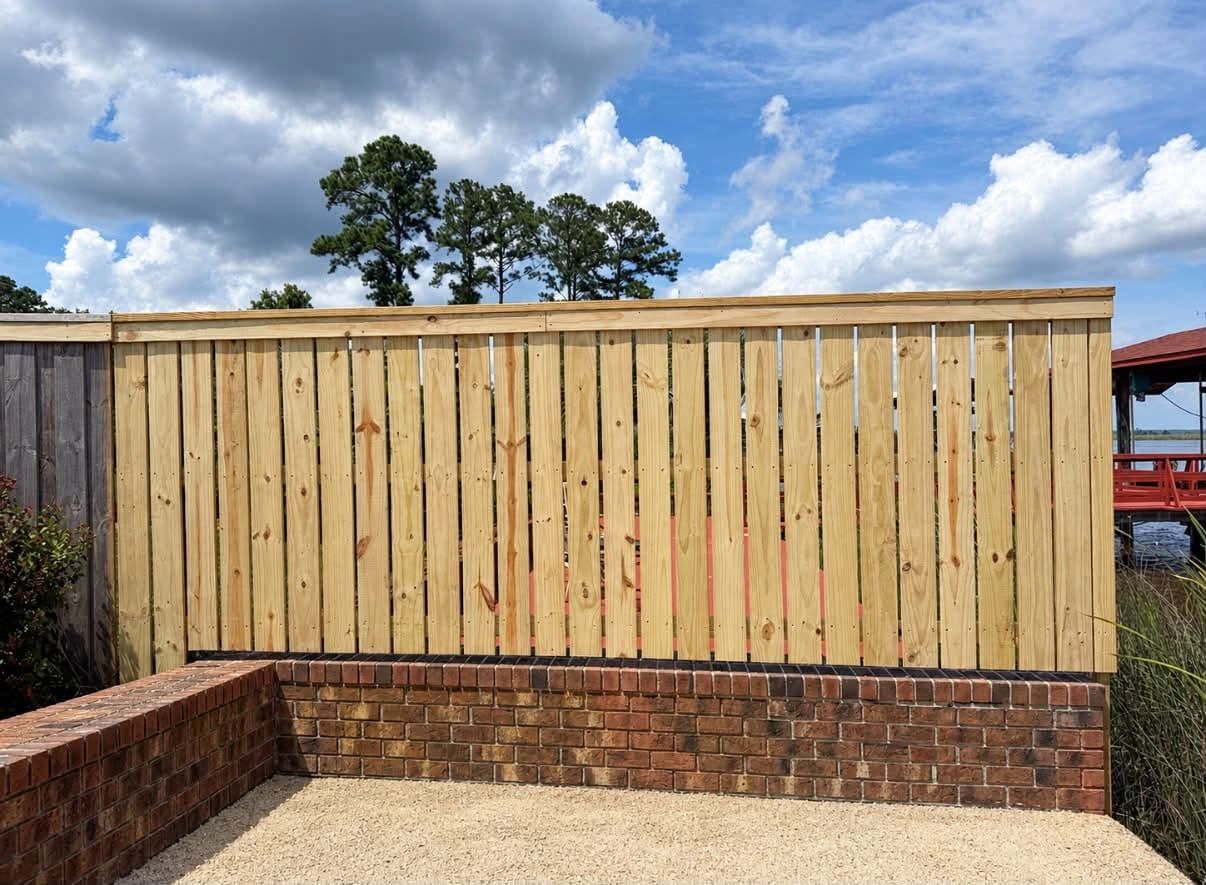 Wooden privacy fence on top of a low brick wall