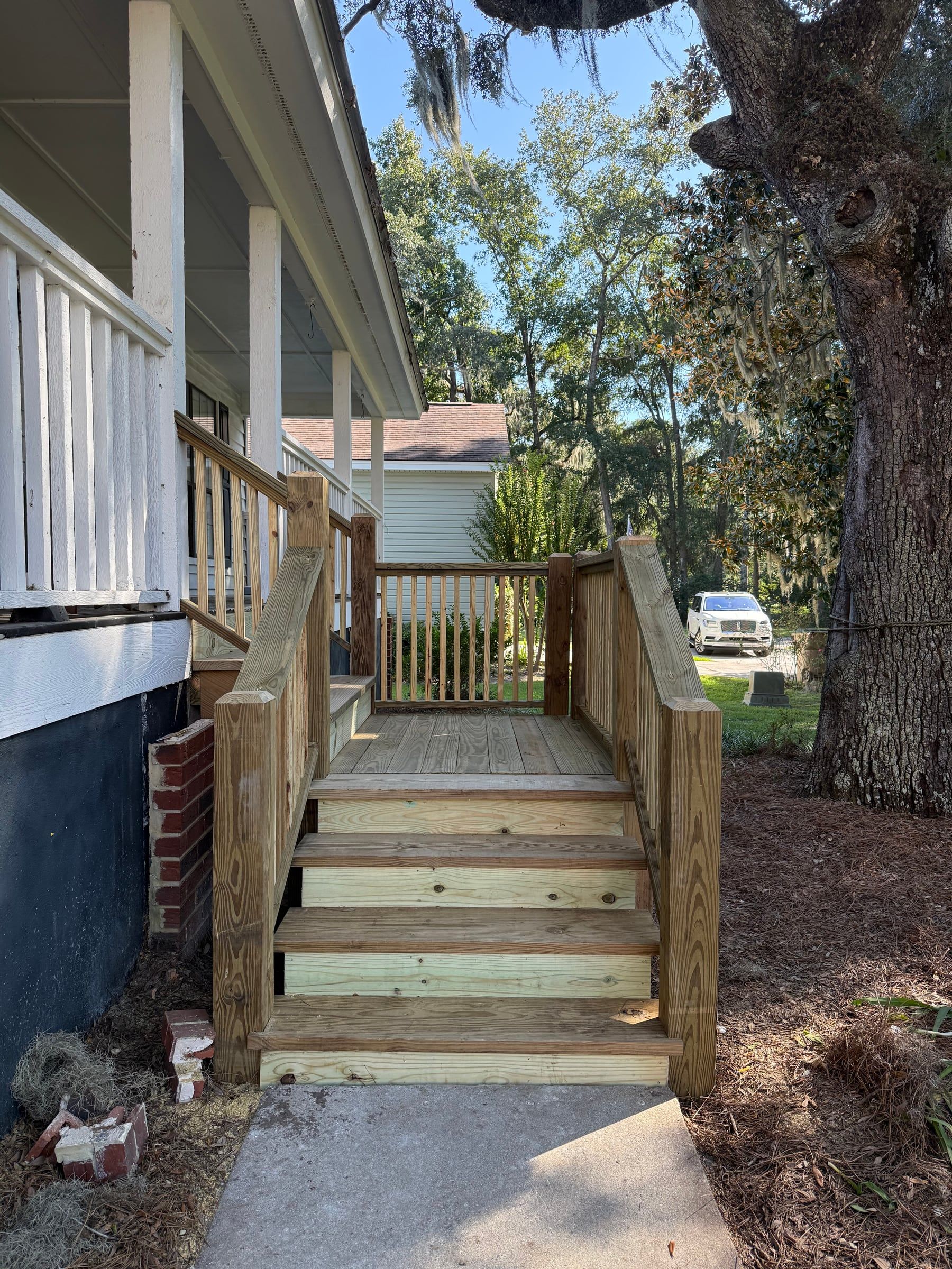 Wooden porch stairs with matching railings beside a raised home